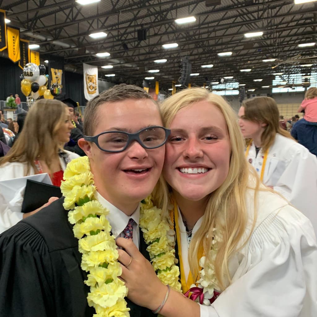Tate Davies and his mother attending graduation wearing floral leis
